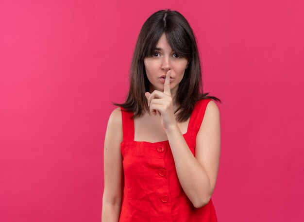 Anxieuse jeune fille caucasienne met le doigt sur la bouche sur fond rose isolé avec copie espace
