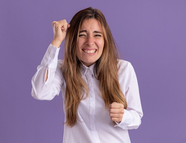 Anxieuse jeune jolie fille caucasienne garde les poings isolés sur un mur violet avec espace de copie