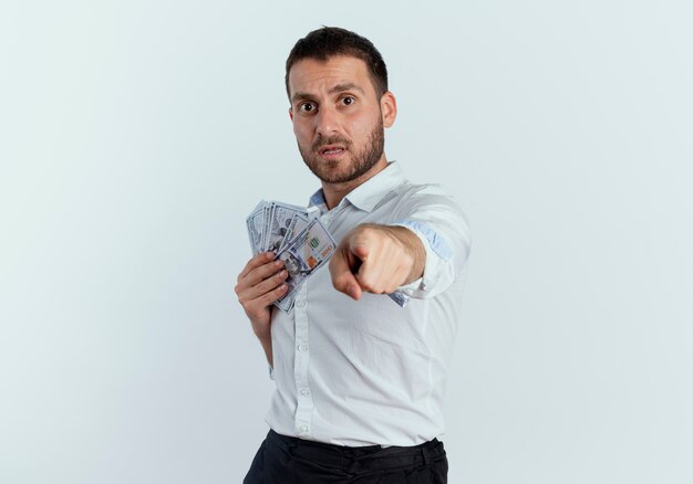 Anxieux bel homme détient de l'argent et des points isolés sur un mur blanc