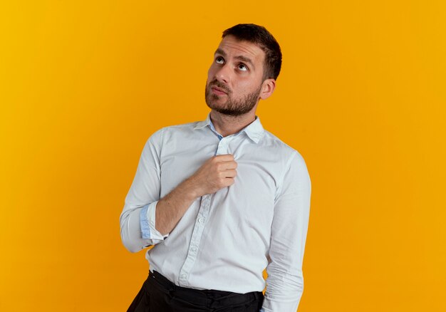 Anxieux bel homme lève les yeux isolé sur un mur orange