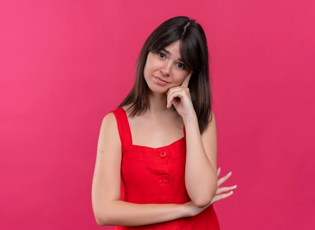 Anxieux jeune fille caucasienne mettant la main sur le menton en regardant la caméra sur fond rose isolé avec copie espace