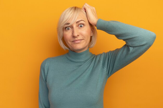 Anxieux jolie blonde femme slave met la main sur la tête sur l'orange