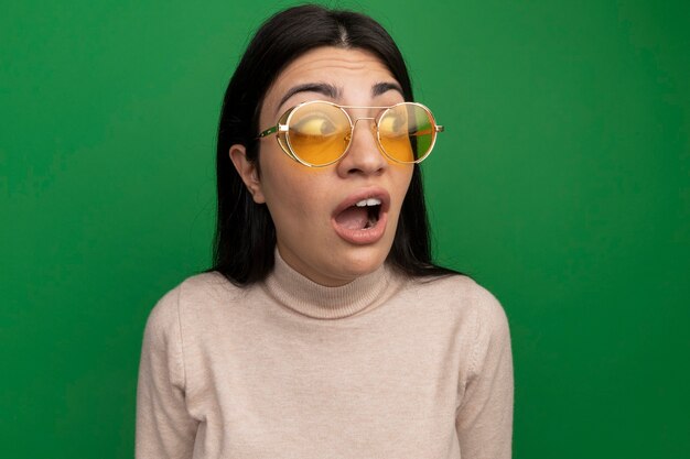 Anxieux jolie fille de race blanche brune à lunettes de soleil regarde le côté sur le vert