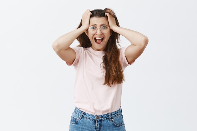 Anxieux et paniqué jeune brune avec des lunettes posant