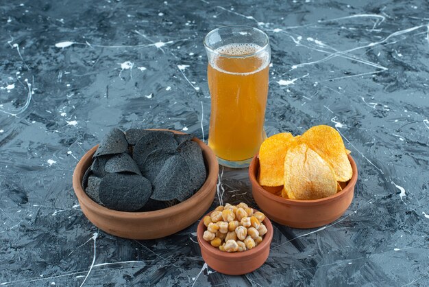 Apéritifs variés dans des bols et un verre de bière, sur le fond bleu.