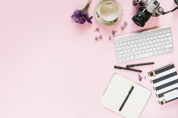 Appareil photo numérique; clavier; feutres et papeterie sur fond rose