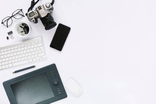 Appareil photo numérique; tablette numérique graphique; clavier; souris et téléphone portable sur fond blanc