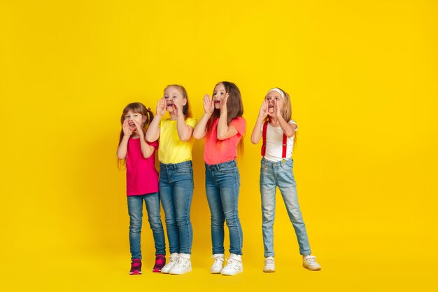 Appel. Enfants heureux jouant et s'amusant ensemble sur le mur jaune du studio.