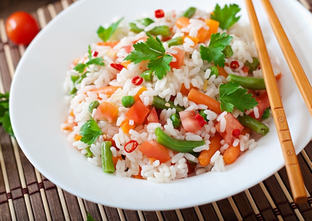 Appétissant riz sain avec des légumes en plaque blanche sur une table en bois.