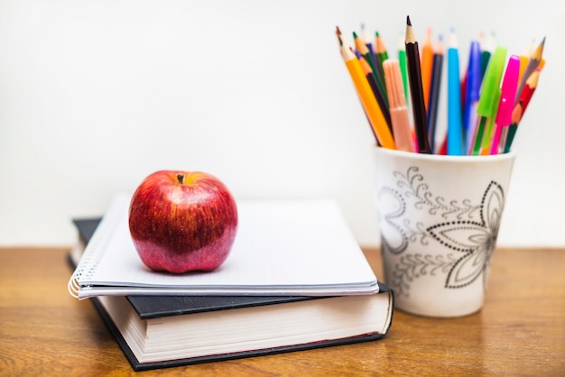 Apple et crayons près de cahier et livre