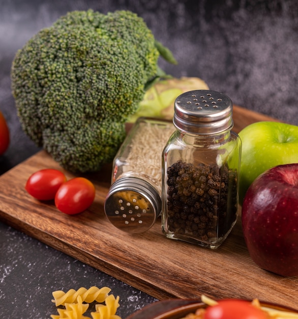 Photo gratuite apple sur une planche en bois avec un pot de graines de poivre