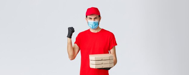 Application de livraison de nourriture épicerie en ligne achats sans contact et concept covid19 Champions de la livraison rapide et sûre dans l'industrie Courrier en uniforme rouge pompe à poing livrer la commande de pizza