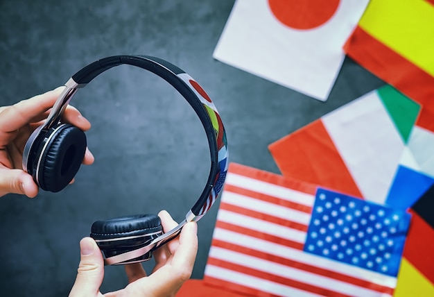 Apprendre des langues étrangères. cours de langue audio. contexte des drapeaux des pays et des écouteurs sur la table.