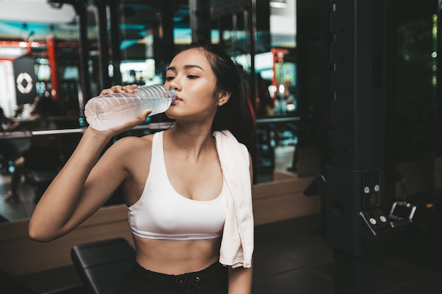 Après l'exercice, les femmes boivent de l'eau provenant de bouteilles et de mouchoirs dans la salle de sport.