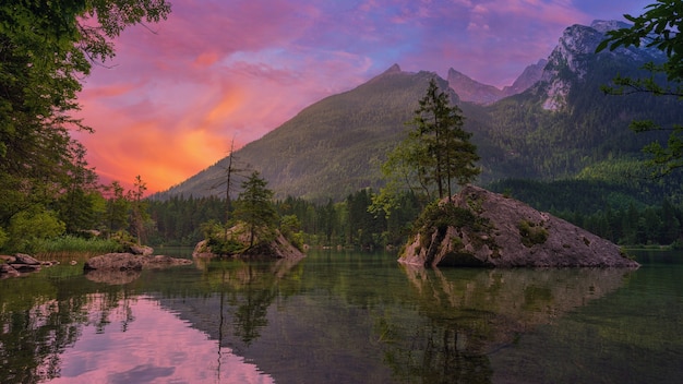 Arbres verts près du lac et de la montagne au coucher du soleil