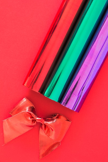 Photo gratuite arc de ruban rouge et paillettes enroulées de papier sur fond rouge