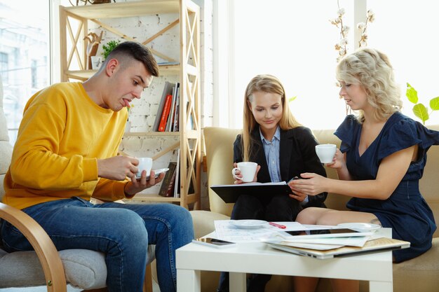 Architecte d'intérieur travaillant avec un jeune couple. Belle famille et designer professionnel ou architecte discutant du concept de futur intérieur, travaillant avec une palette de couleurs, des dessins de pièce dans un bureau moderne.