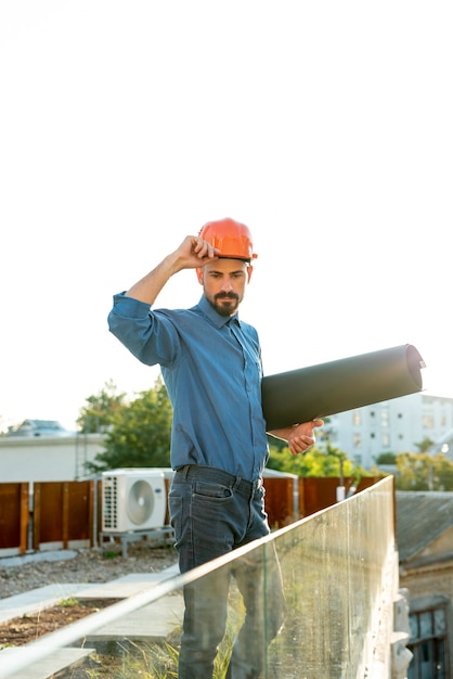 Architecte tenant un plan avec un casque de protection