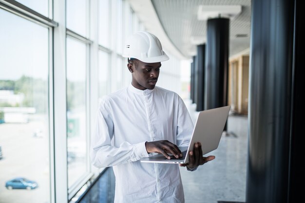 Architecte travaillant avec ordinateur et plans au bureau