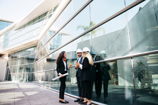 Photo gratuite architectes portant des casques devant un bâtiment en verre