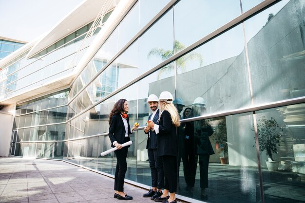 Architectes portant des casques devant un bâtiment en verre