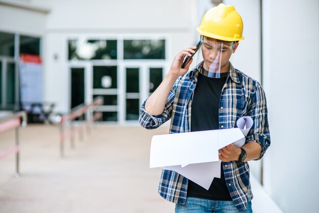 Les architectes tiennent des plans d'étage et parlent au téléphone.