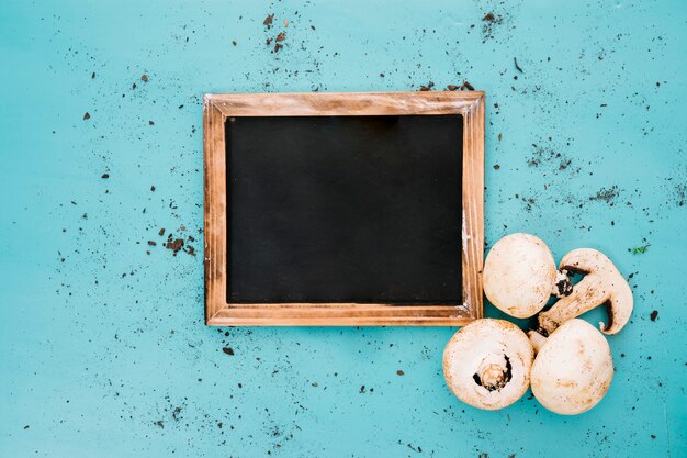 Ardoise à côté de champignons sur un fond sale