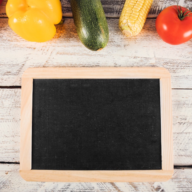 Photo gratuite ardoise vierge avec des aliments sains sur fond en bois