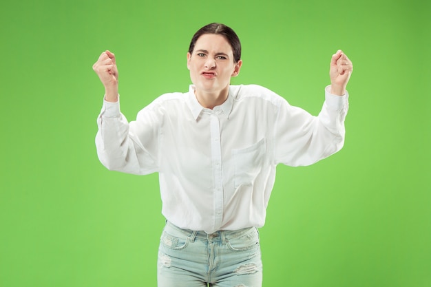 Argumenter, argumenter le concept. Beau portrait de femme demi-longueur isolé sur fond de studio vert. Jeune femme surprise émotionnelle regardant la caméra. Émotions humaines, concept d'expression faciale