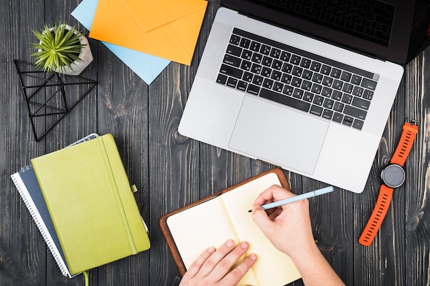 Photo gratuite arrangement de bureau vue de dessus avec une personne écrivant