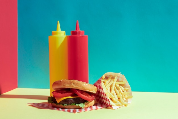 Arrangement avec de délicieux burger et des bouteilles de sauce