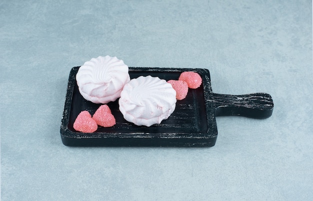 Arrangement de dessert de morceaux de marmelade et de biscuits sur un plateau noir sur marbre.