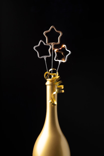 Photo gratuite arrangement de fête du nouvel an vue de face avec bouteille dorée