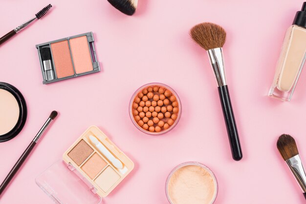 Arrangement de maquillage et accessoires cosmétiques sur fond rose