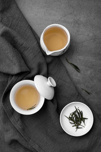 Arrangement plat avec des tasses à thé et des herbes