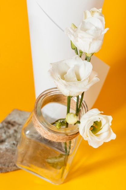 Photo gratuite arrangement avec des roses blanches dans un vase avec un cône en papier