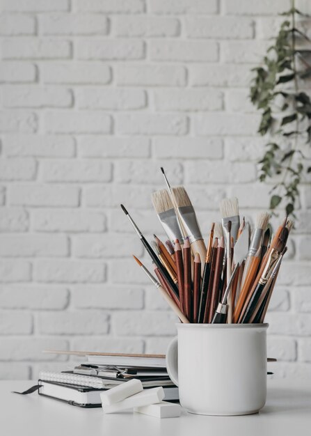 Arrangement avec stylos et pinceaux en tasse