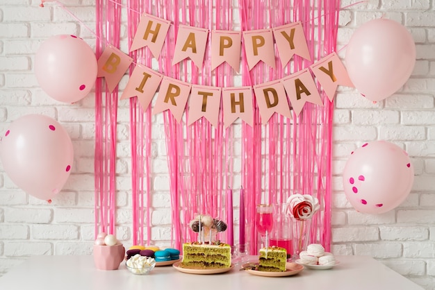 Photo gratuite arrangement de table pour un anniversaire avec gâteau et bannière de joyeux anniversaire