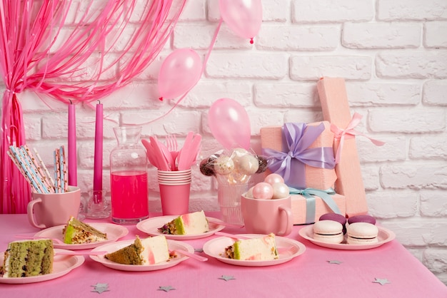 Arrangement de table pour un anniversaire avec des tranches de gâteau et des macarons