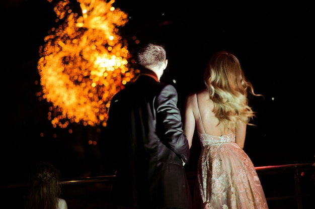 L'arrière du couple amoureux qui regarde les feux d'artifice