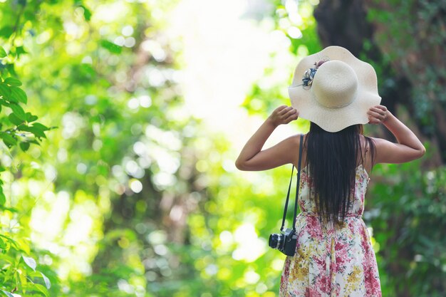 L'arrière de la fille de bonheur portant un chapeau de paille dans le jardin