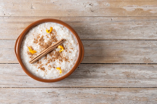 Photo gratuite arroz con leche riz au lait à la cannelle dans un bol d'argile sur une table en bois