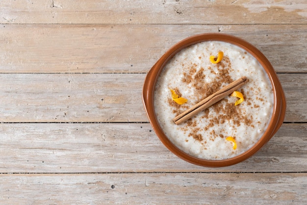Photo gratuite arroz con leche riz au lait à la cannelle dans un bol d'argile sur une table en bois