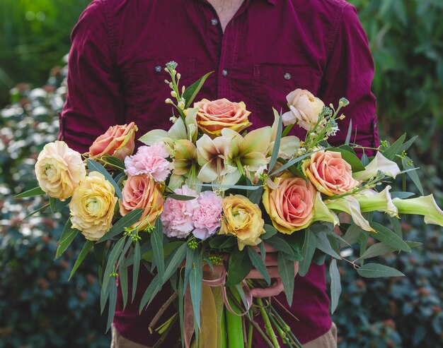 Art floral, guirlande de fleurs mélangées entre les mains d'un homme