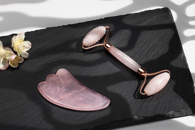 Photo gratuite articles et fleurs de gua sha rose à angle élevé