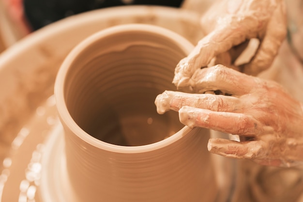 Artisan façonne le pot en terre avec ses mains sur le tour de potier