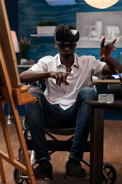 Artiste afro-américain avec casque de réalité virtuelle imaginant une illustration de dessin tout en travaillant sur un chef-d'œuvre d'art dans un studio de créativité. Homme handicapé dessin croquis sur toile à l'aide de penci graphique