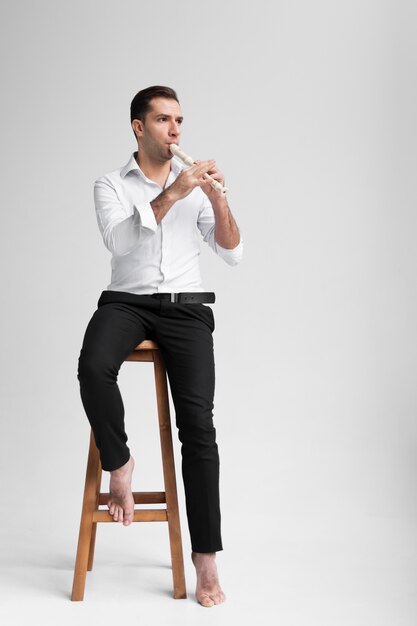 Artiste assis sur une chaise et jouant de la flûte