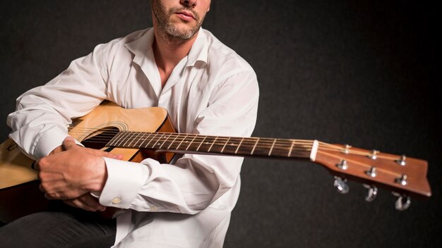 Artiste en chemise blanche tenant sa guitare acoustique