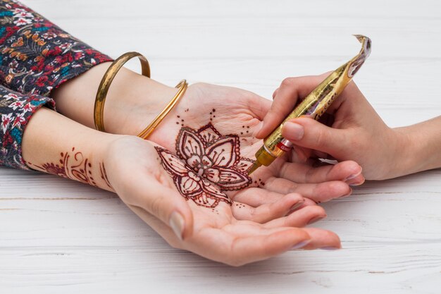 Artiste fabriquant du mehndi sur des paumes de femmes